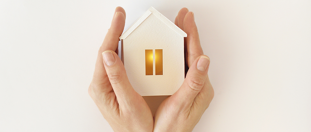 家のミニチュアを包む両手のひら